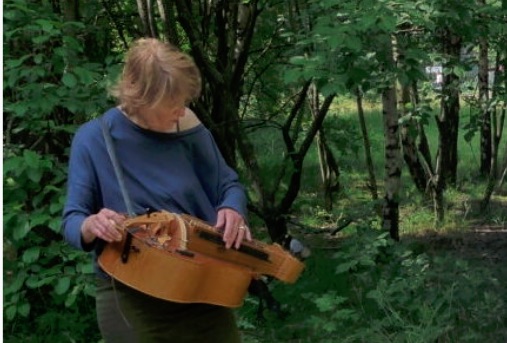 Stevie Wishart playing hurdy gurdy in a forest